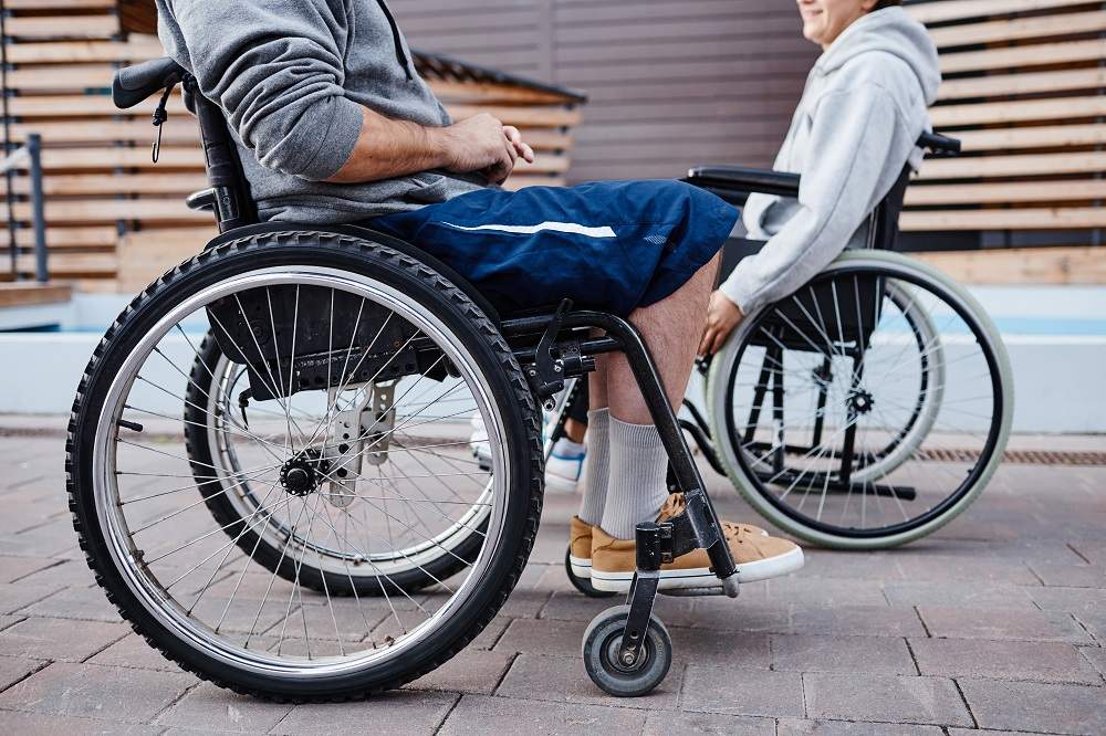 Close-up of people with disability sitting in wheelchairs and talking to each other they spending time outdoors
